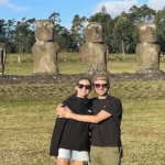 Two tourists posing in front of the moai statues at Ahu Akivi, Easter Island.